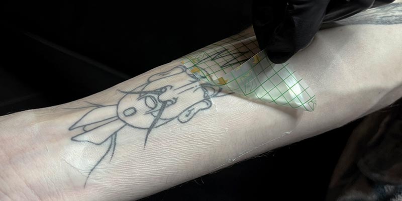 Tatoueur appliquant un pansement seconde peau sur un tatouage fraîchement réalisé